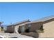 Tan desert home with a gray roof, gravel yard, and light colored front door on a sunny day at 2520 E Ambush St, Pahrump, NV 89048