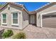 Close up of front door, exterior windows, and two car garage, with gravel and sparse plants at 326 Zenith Crest St, Henderson, NV 89015