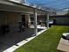 Backyard patio area with artificial turf, covered pergola, outdoor seating, and block wall fence at 3601 Slapton Ave, North Las Vegas, NV 89031