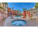 Community pool area featuring a hot tub, lounge chairs, palm trees, and several condo buildings at 63 E Agate Ave # 202, Las Vegas, NV 89123