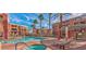 A community pool area with multiple buildings, a hot tub, and lounge chairs amidst palm trees at 63 E Agate Ave # 202, Las Vegas, NV 89123