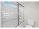 Clean bathroom with a sliding glass door and shower, all tiled in white at 6460 Raven Hall St, North Las Vegas, NV 89084