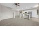 Open-concept living space with gray carpet, a ceiling fan, staircase and a modern kitchen in the background at 6460 Raven Hall St, North Las Vegas, NV 89084
