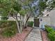 Landscaped front yard with mature trees and shrubs, walkway leading to a wooden gate, creating a welcoming entrance at 7952 Lonette Ave, Las Vegas, NV 89147
