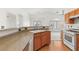 Well-lit kitchen showcasing wood cabinets, stone countertops, a white range, and a view into the adjacent living area at 89 Day Trade St # 1, Henderson, NV 89074