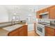 Open kitchen with wood cabinets, breakfast bar, stainless steel sink, and a view of the living room and natural light at 89 Day Trade St # 1, Henderson, NV 89074