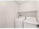 A compact laundry room features a white washer and dryer, and a shelf for storage at 89 Day Trade St # 1, Henderson, NV 89074
