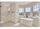 Elegant bathroom featuring a freestanding tub and walk-in shower, complemented by natural light from large windows at 9722 Rocket Grove Ct, Las Vegas, NV 89178