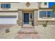 Close up shot of the house entrance that includes a stone facade, blue front door, brick steps, and desert landscaping at 9722 Rocket Grove Ct, Las Vegas, NV 89178