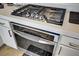 Close-up of stainless steel oven and stovetop with white cabinets and quartz countertops at 9864 Maspalomas St, Las Vegas, NV 89178