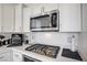 Close-up of stainless steel microwave and stovetop with white cabinets and quartz countertops at 9864 Maspalomas St, Las Vegas, NV 89178