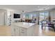 Open-concept living area with tile flooring, large windows, and kitchen island with white cabinets at 9864 Maspalomas St, Las Vegas, NV 89178