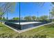 Outdoor sand volleyball court in a fenced-in area, with lush grass and shaded mature trees for a resort-style experience at 10325 Sweet Fennel Dr, Las Vegas, NV 89135