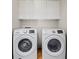Bright laundry room with white front-load washer and dryer and upper cabinets at 10918 Avenzano St, Las Vegas, NV 89141