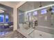 A bright bathroom featuring a glass enclosed shower and tub, complete with elegant fixtures and stylish gray stone tile at 12544 Claymore Highland Ave, Las Vegas, NV 89138