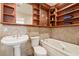 Elegant bathroom features decorative wood shelving, marble tile, and a pedestal sink at 159 Coastal Pier Ct, Henderson, NV 89002
