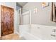 Bright bathroom features a shower over tub with glass screen, a wooden door, and a neutral color palette at 3337 Partridge Run St, Laughlin, NV 89029