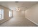 A large carpeted bedroom with two windows and neutral walls illuminated by a ceiling fan at 5110 N Valadez St, Las Vegas, NV 89149