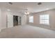 A large carpeted bedroom with two windows and doors to a bathroom and a stairwell at 5110 N Valadez St, Las Vegas, NV 89149