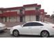 View of a two-story building with a red staircase and a white car in the foreground at 5388 Swenson St # 26, Las Vegas, NV 89119