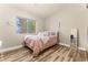 A cozy bedroom with a soft pink comforter, a window, and wood-look flooring at 5452 Desert Spring Rd, Las Vegas, NV 89149