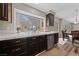 Bright kitchen featuring dark cabinets, stainless steel dishwasher, tile countertops, with view to dining area at 5452 Desert Spring Rd, Las Vegas, NV 89149