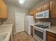 Kitchen featuring oak cabinets, white appliances, and tiled floors at 7135 S Durango Dr # 106, Las Vegas, NV 89113