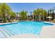 Community pool area with lounge chairs and umbrellas surrounded by lush landscaping at 7255 W Sunset Rd # 2030, Las Vegas, NV 89113