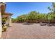 Spacious backyard featuring a covered patio, rock landscaping, and mature trees, perfect for outdoor living at 7286 Mount Kearsarge St, Las Vegas, NV 89131
