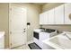 Efficient laundry room with a washer, dryer, sink, and storage cabinets for convenience at 7286 Mount Kearsarge St, Las Vegas, NV 89131