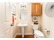 Well-lit powder room with pedestal sink, decorative mirror and fixtures, and wood look flooring at 7540 Flowing Stream Dr, Las Vegas, NV 89131