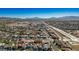 Wide aerial shot of a neighborhood situated near a highway, surrounded by open spaces and distant mountains at 816 Sandsprings St, Henderson, NV 89011