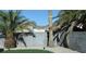 Backyard view featuring block wall, desert landscaping, lush green turf, and elegant palm trees, creating a private oasis at 851 Brahma Ln, Henderson, NV 89002