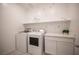 Well-lit laundry room with modern washer and dryer, storage, and decorative leafy decals at 9256 Alden Pointe Ct, Las Vegas, NV 89143