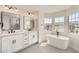 Bright bathroom featuring double vanity, modern fixtures, standalone tub, and large windows at 9712 Rocket Grove Ct, Las Vegas, NV 89178