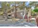 Condo exterior featuring a private entrance with stairs and a beautifully landscaped yard with mature trees at 10205 Camborne Ave # 104, Las Vegas, NV 89144