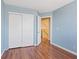 Light blue bedroom with wood-look flooring, closet with sliding doors, and a bright view at 1711 Ember Glow Cir, Las Vegas, NV 89119