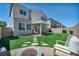 Expansive backyard with well-manicured faux grass, fire pit, patio, and covered pergola with stylish outdoor seating at 2024 Mystic Wave Rd, North Las Vegas, NV 89031
