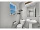 Well-lit bathroom features a pedestal sink, toilet, and a window at 2024 Mystic Wave Rd, North Las Vegas, NV 89031