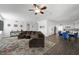 Open-concept living room with a ceiling fan, brown sectional sofa, and colorful rug at 2229 Armacost Dr, Henderson, NV 89074