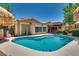 Inviting backyard pool featuring Baja shelf, tropical landscape and thatch umbrellas at 3877 Platis Cir, Las Vegas, NV 89103