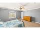 Bedroom with a large window, neutral carpet, ceiling fan, and a wooden dresser at 5917 Horsehair Blanket Dr, North Las Vegas, NV 89081