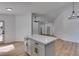 Bright, minimalist kitchen with a white island, light wood floors, and modern lighting fixtures at 6126 Bedrock Ct, North Las Vegas, NV 89031