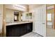 Well-lit bathroom with double sinks, granite counters, dark wood cabinets, and white trim at 6897 Linda Creek Ct, Las Vegas, NV 89178