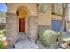 Charming home entrance with stone columns, arched doorway, and a welcoming red front door at 6897 Linda Creek Ct, Las Vegas, NV 89178