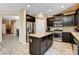 Open kitchen with dark wood cabinets, stainless appliances, granite counters, and views into other living areas at 6897 Linda Creek Ct, Las Vegas, NV 89178