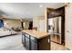 Stylish kitchen island with granite countertop, stainless steel refrigerator, and open layout to the living room at 6897 Linda Creek Ct, Las Vegas, NV 89178