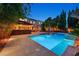 Inviting backyard featuring pool with water features, outdoor bar area, lush landscaping, and well-lit outdoor spaces at 7033 Twin Forks Peak St, Las Vegas, NV 89166