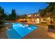 Backyard pool with a swim-up bar, a lush lawn, and an outdoor living space at dusk at 7033 Twin Forks Peak St, Las Vegas, NV 89166