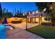 Backyard patio and pool with a tiki bar, grassy yard, and covered patio, ideal for evening relaxation at 7033 Twin Forks Peak St, Las Vegas, NV 89166